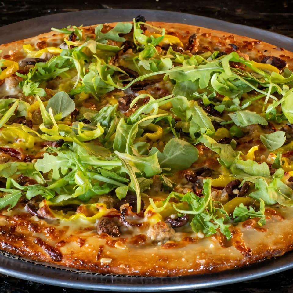Task Force Pizza's pizza, topped with fresh arugula, yellow peppers, olives, and sausage.