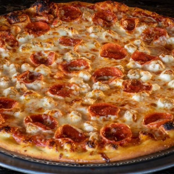 Close-up of a Task Force Pizza pepperoni and chicken pizza with melted cheese.