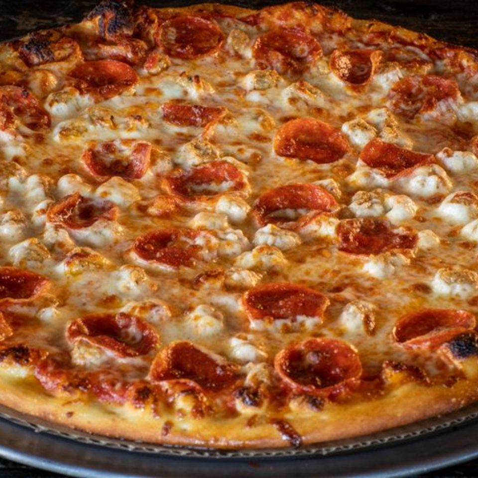 Close-up of a Task Force Pizza pepperoni and chicken pizza with melted cheese.