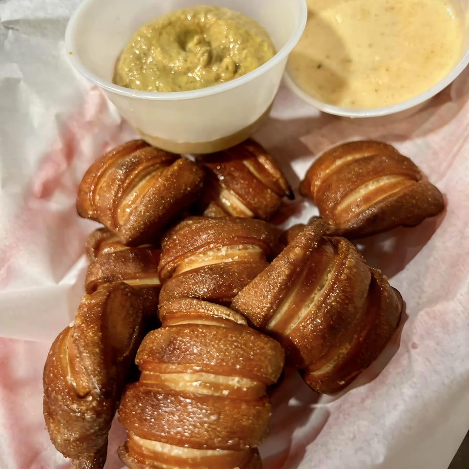 Task Force Pizza's pretzel bites with mustard and cheese dipping sauces in white cups.